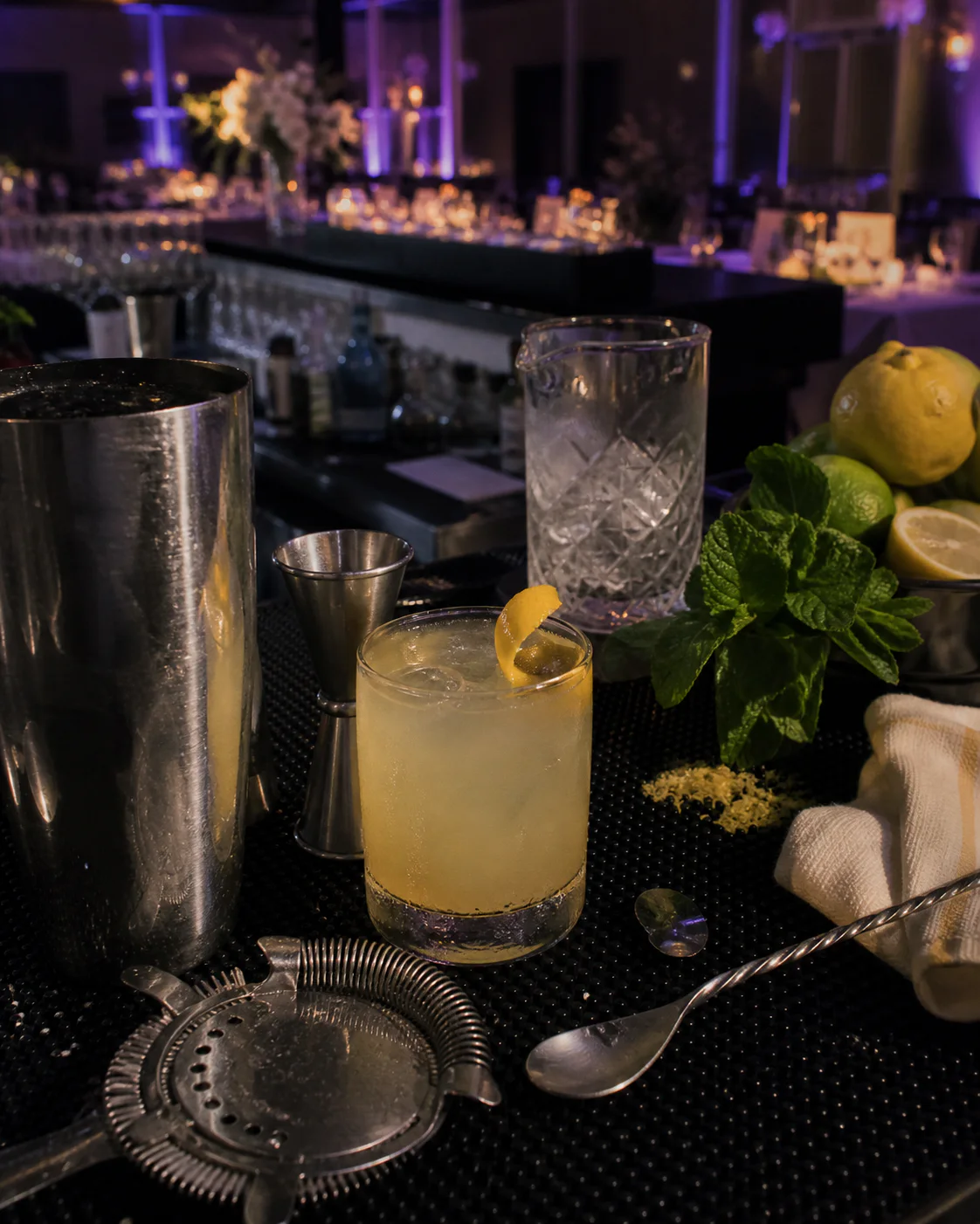 A naturally arranged cocktail station with professional tools, fresh garnishes and a finished drink