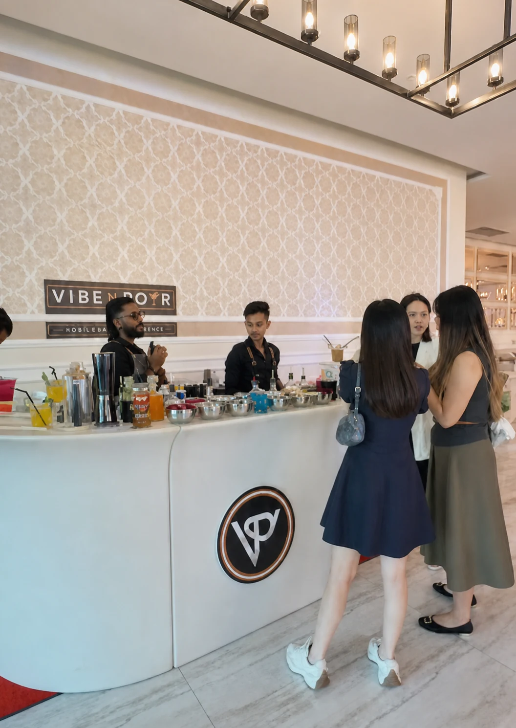 Guests chatting with bartenders at the white Vibe N Pour mobile bar.