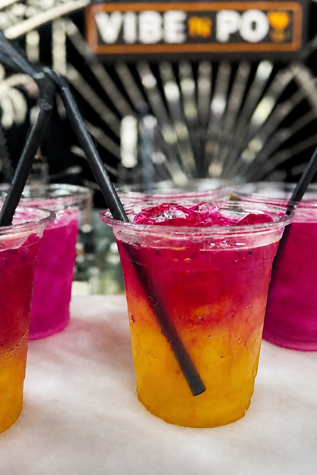 Yellow and magenta layered drinks served over ice with black straws.